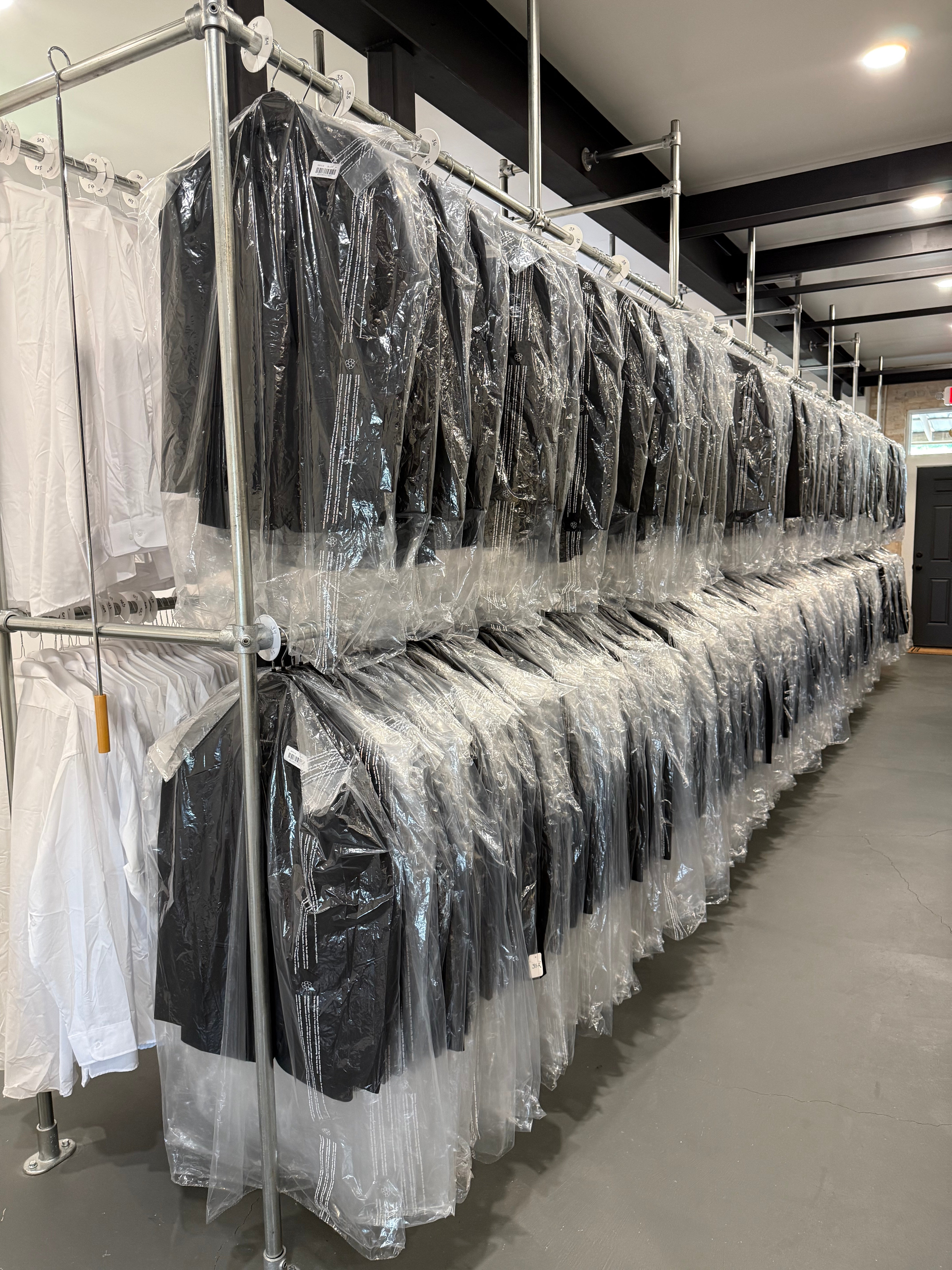 warehouse image of several hundred Waring Tuxedos tuxedos on hanging racks