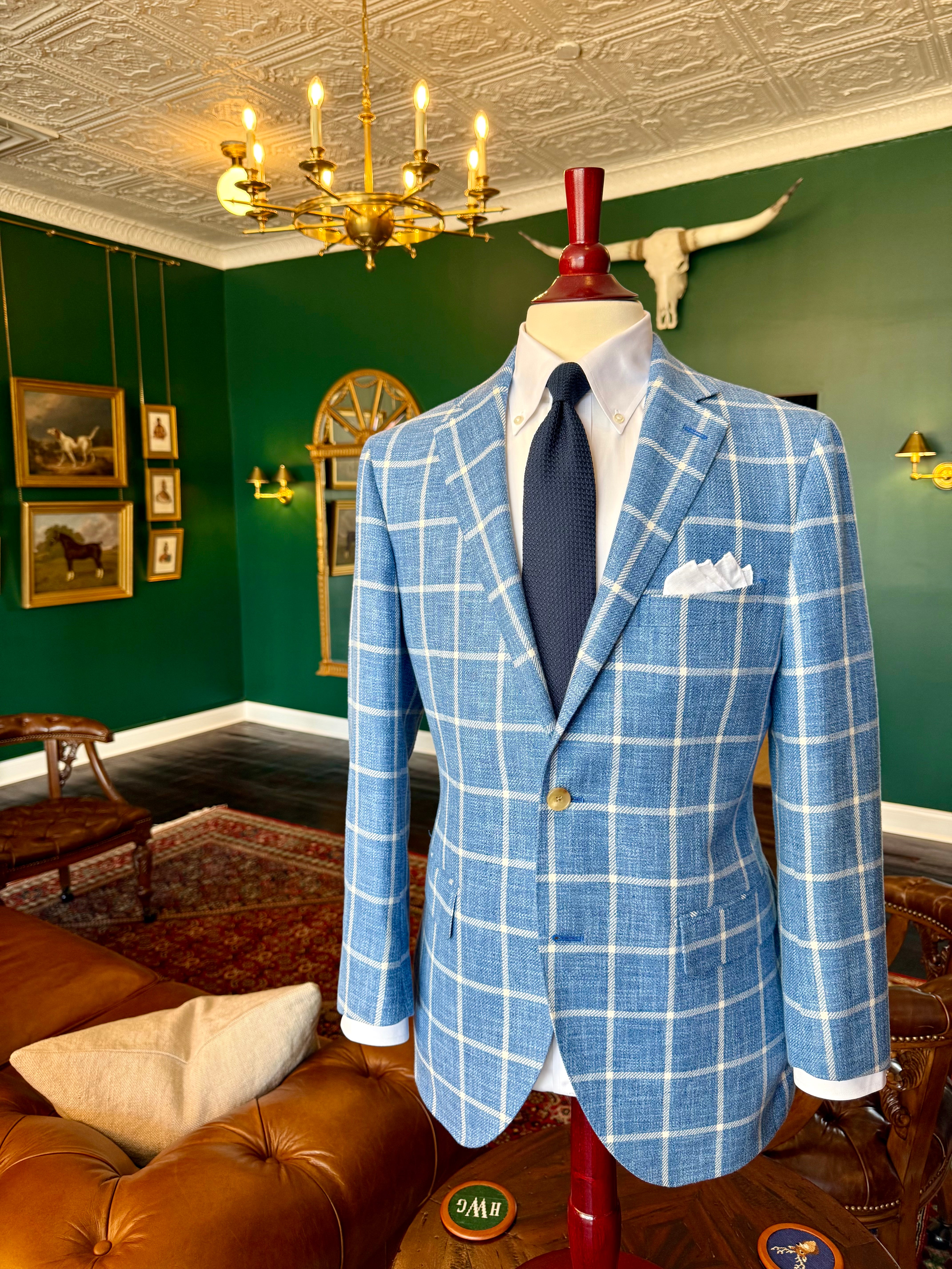 A Light blue and white windowpane sport coat at Waring Tuxedos, shown on a mahogany mannequin in our Fort Worth showroom with green walls, oil paintings, and clubroom decor