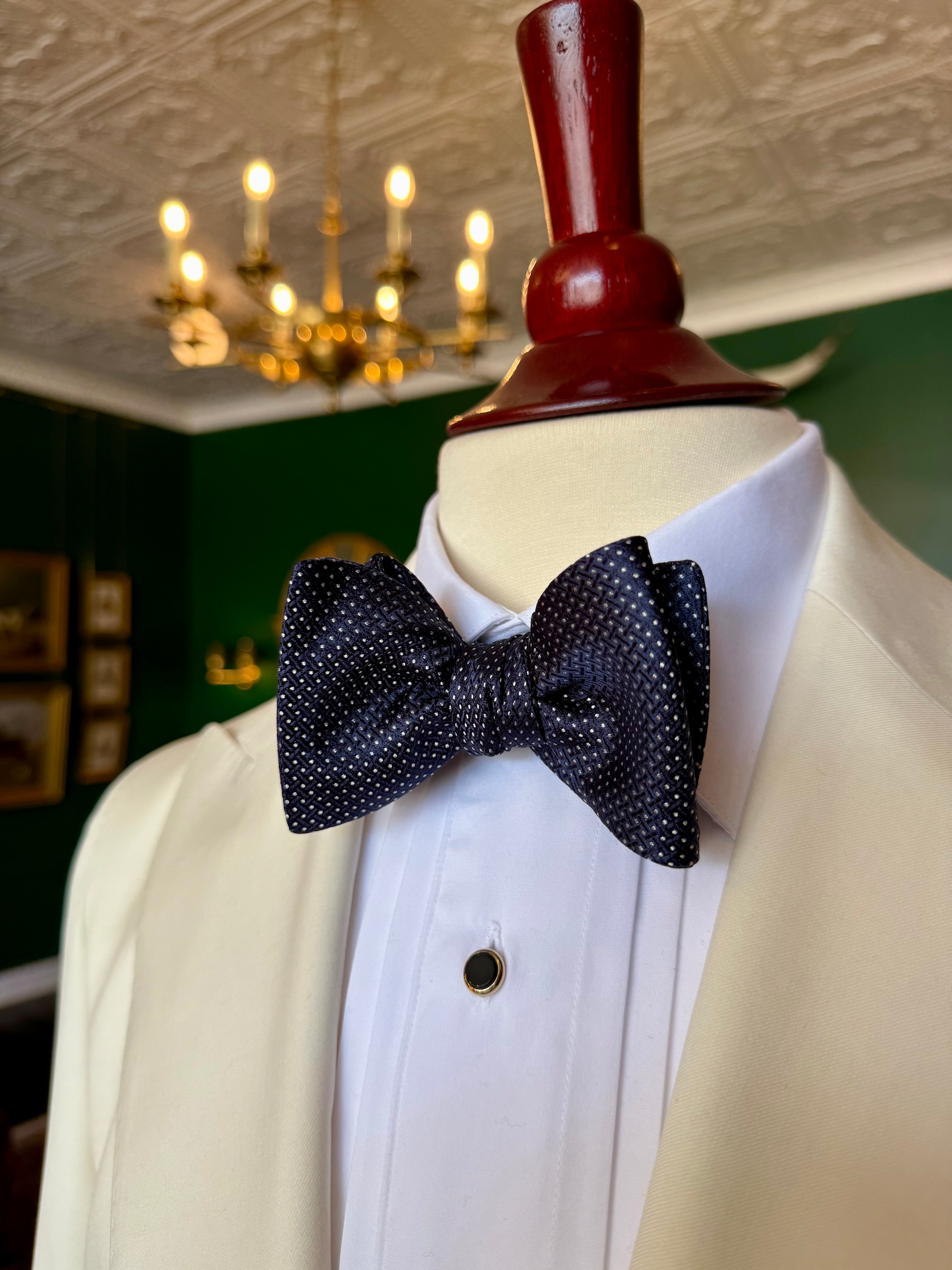 Navy Runnymede Bow Tie from Waring Collection at Waring Tuxedos in Fort Worth, displayed on mahogany mannequin.