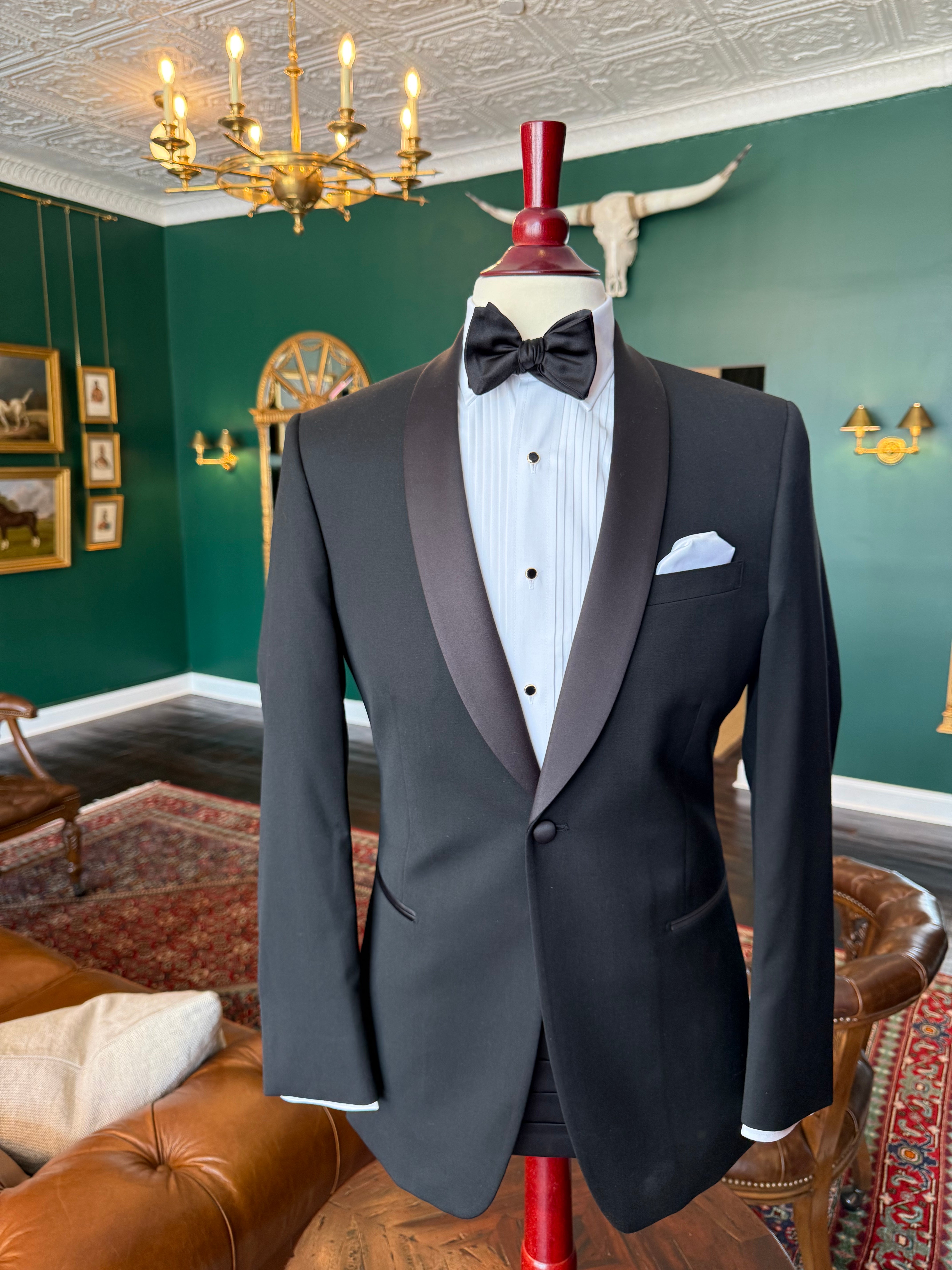 Classic black shawl lapel tuxedo with satin detailing on mahogany mannequin, available for rent at Waring Tuxedos in Fort Worth.