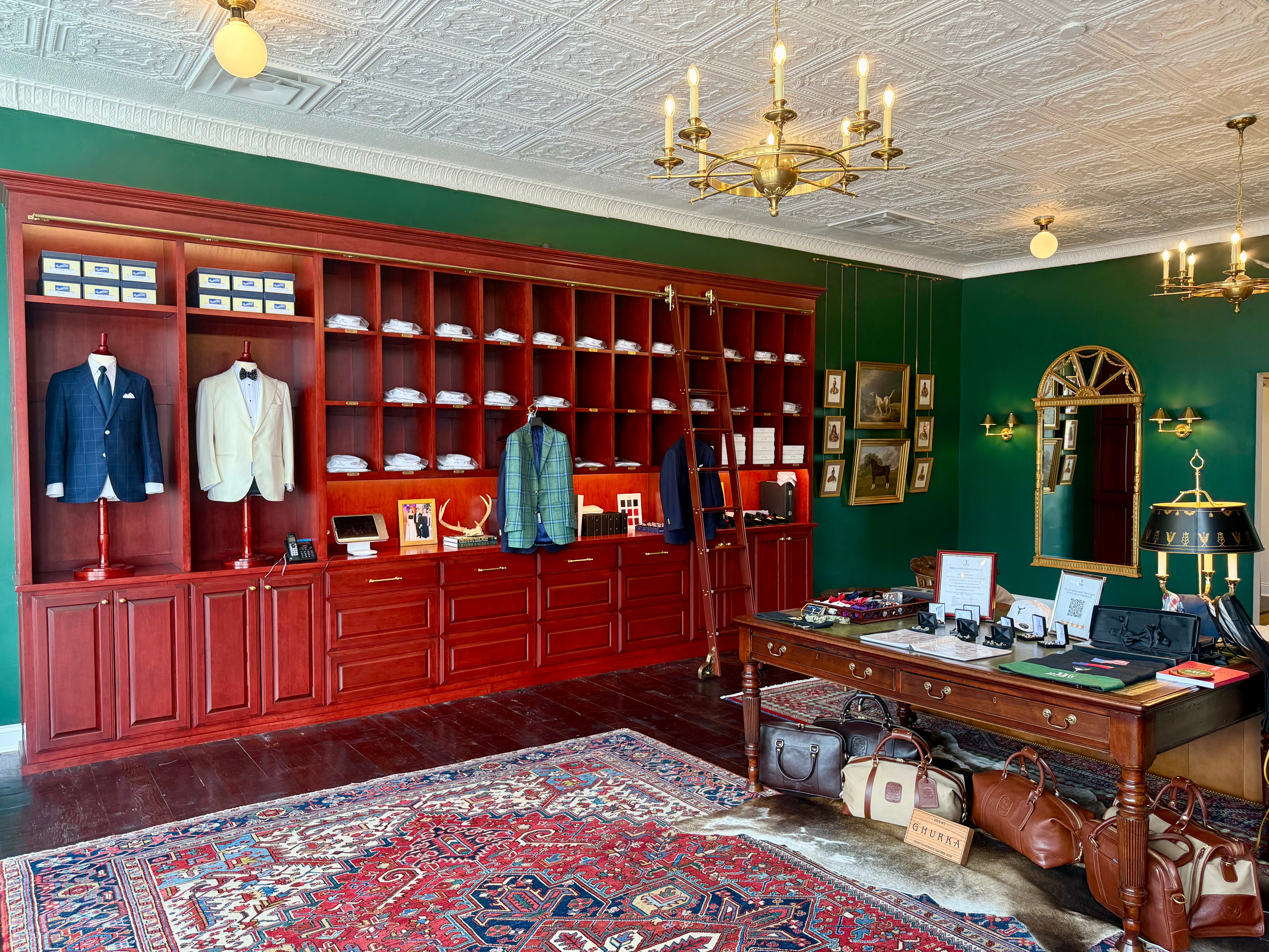 Waring Tuxedos custom suit and dinner jacket on mahogany mannequins in mahogany shirt shelving against green walls in traditional tailor shop.