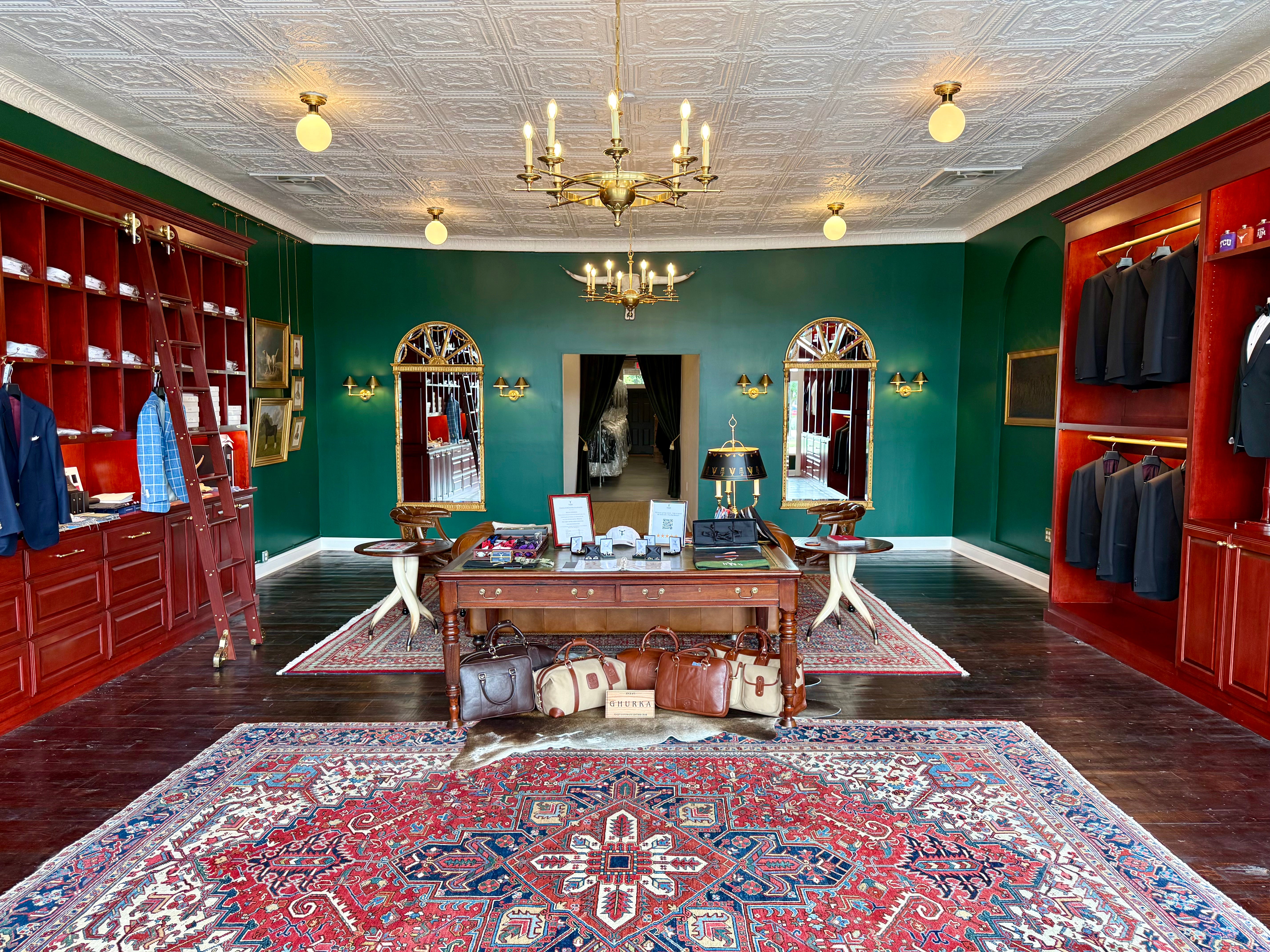 Interior of Waring Tuxedos in Fort Worth, showcasing refined formalwear displays in mahogany shelving against hunter green walls, custom clothing, and premium accessories in a classic, club-inspired setting.