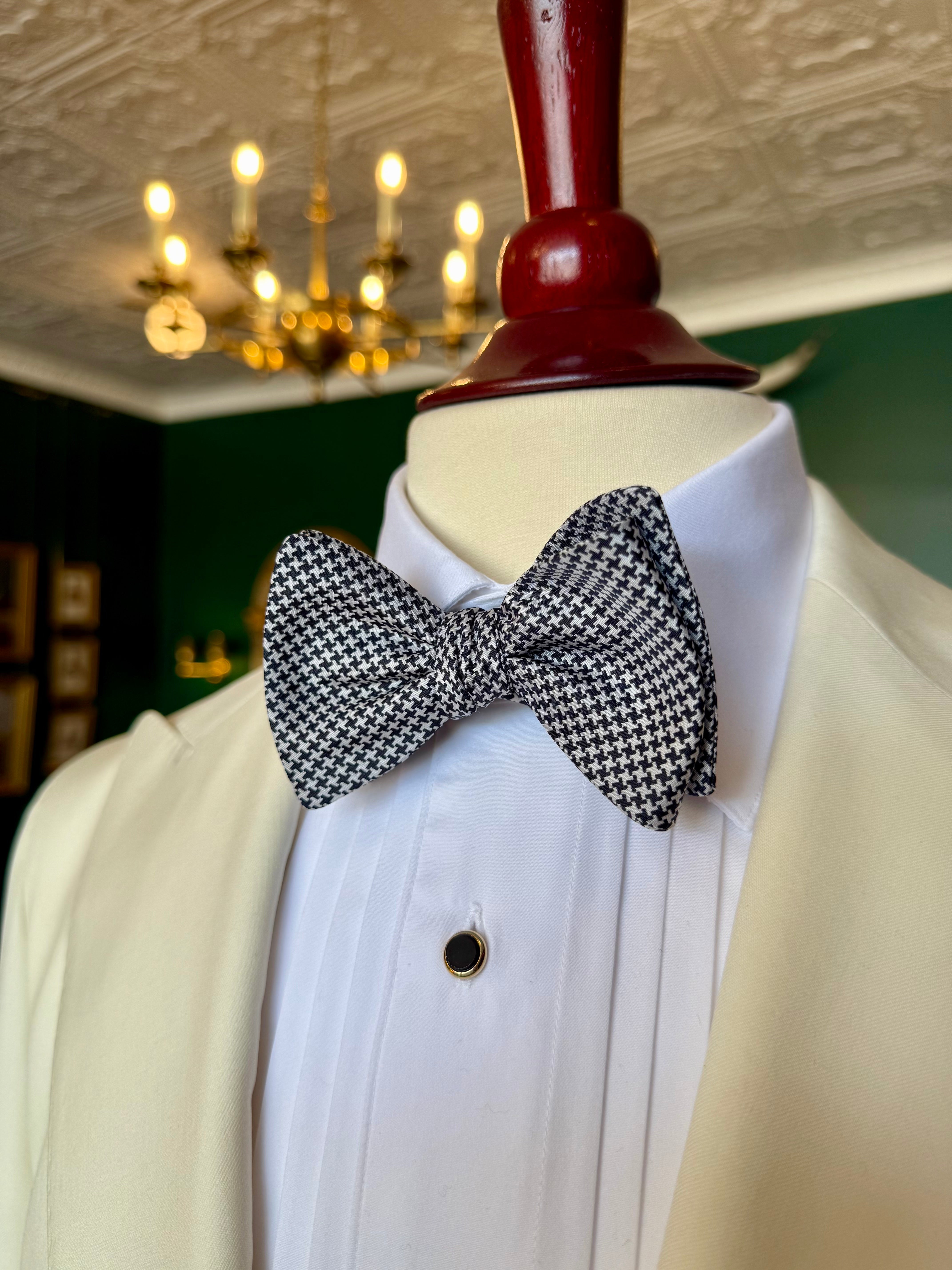 Houndstooth Bow Tie from Waring Collection at Waring Tuxedos in Fort Worth, displayed on mahogany mannequin.