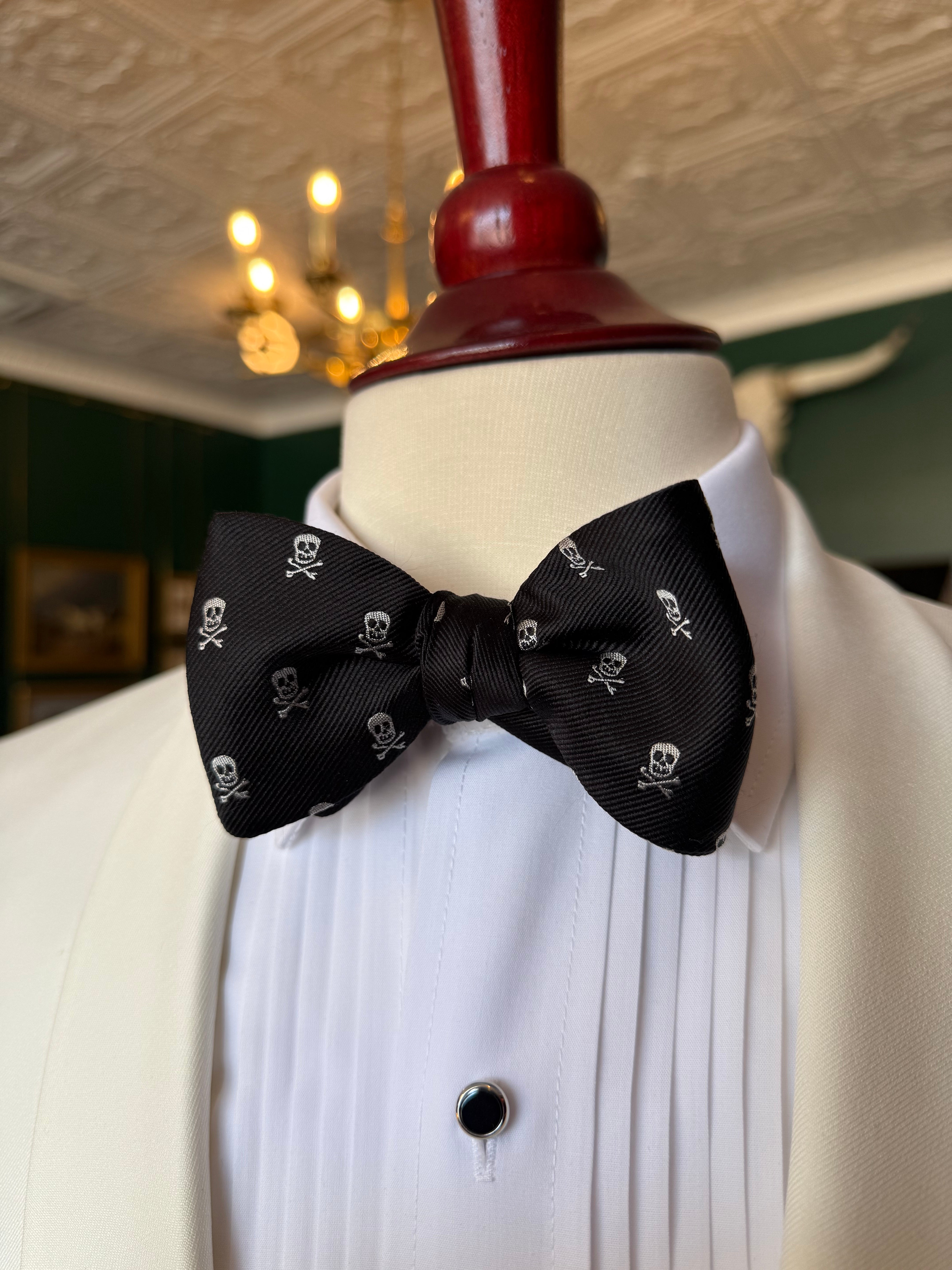 Skull and Bones Bow Tie from Waring Collection at Waring Tuxedos in Fort Worth, displayed on mahogany mannequin.
